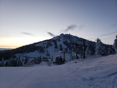 A picturesque view of Mt. Ashland ski resort in Oregon featuring a ski lift amidst a winter sports scene with a skier in action. The backdrop of the majestic mountain enhances the scenic charm.