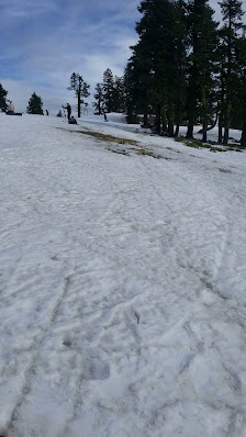 A skier enjoying a snowy day at Mt. Ashland ski resort in Oregon USA. A ski lift and ski resort serve as the backdrop for this winter sports scene. A snowmobile is also visible in the background.