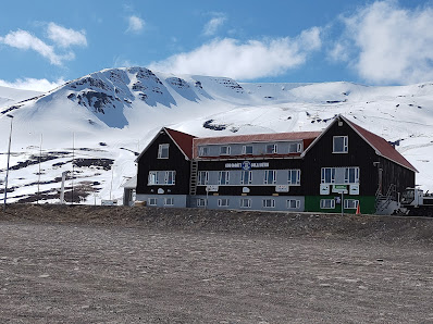 View of Hlíðarfjall ski resort in Northeast Iceland featuring a mountain hut a challet and a lodge against a backdrop of snow-covered slopes embodying a quintessential winter sports center.