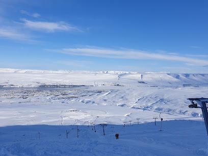 Winter sports scene at Hlíðarfjall ski resort in Akureyri, Northeast Iceland, featuring a challet and picturesque snow-covered slopes.