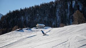 A scenic winter view at Sportbahnen Eischoll Augstbordregion in Switzerland with a charming chalet and skiers enjoying the snowy slopes of the ski resort.