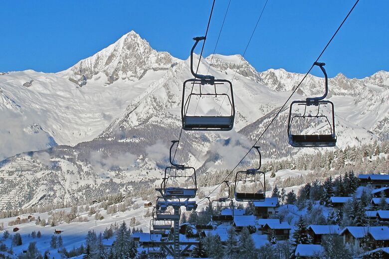 View of Sportbahnen Eischoll Augstbordregion in Switzerland featuring a ski lift leading up to a charming chalet surrounded by stunning winter scenery indicative of a busy ski resort.