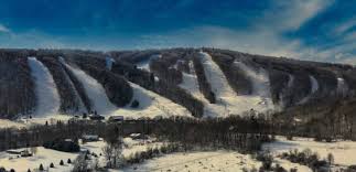 Winter sports enthusiasts enjoying a day at the Song Mountain ski resort in Tully, New York, with snow-covered slopes and a charming chalet in the serene winter scenery.