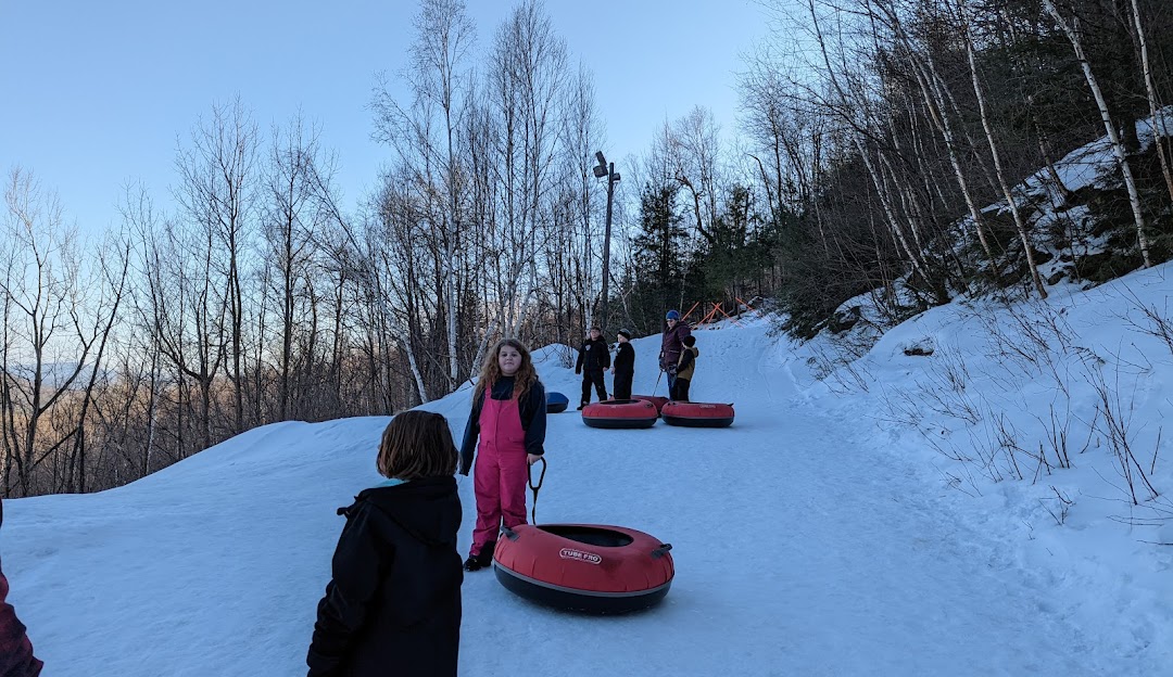 Winter sports enthusiasts enjoy skiing down the snowy slopes of Black Mountain in Rumford, Maine. The ski resort's lift adds scenic beauty to the serene, snow-covered environment.
