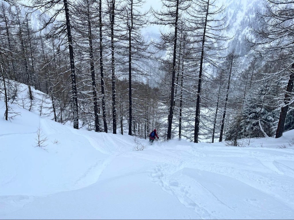 Prali in Italy - a person walking through the snow covered forest.