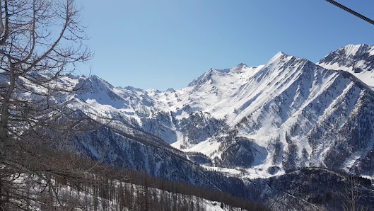 Picture of a charming chalet nestled in the striking winter terrain of Prali, Turin's beloved ski resort. Majestic mountain ranges cradle the scene, highlighting the serenity of Piedmont's winter wonderland.
