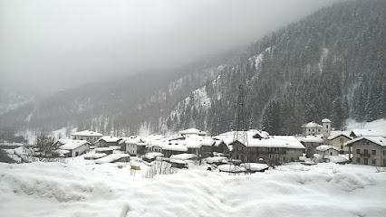 Ski resort scene in Prali, Turin, featuring winter sports enthusiasts amidst snowy slopes and a quaint chalet nestled in the scenic wintry surroundings of Piedmont, Italy.