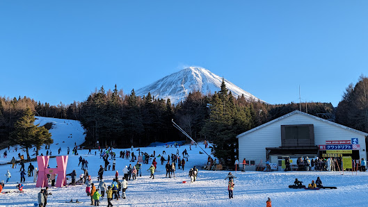 Winter scene at Fujiten Snow Resort in Japan, featuring skiers on mountain slopes, snow-covered landscape, and resort facilities in the backdrop.