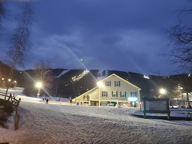 A ski resort at Jiminy Peak in Hancock, Massachusetts, bustling with activity. Skiers utilize the ski lift against the striking backdrop of a winter sports scene with pristine, snow-covered scenery.