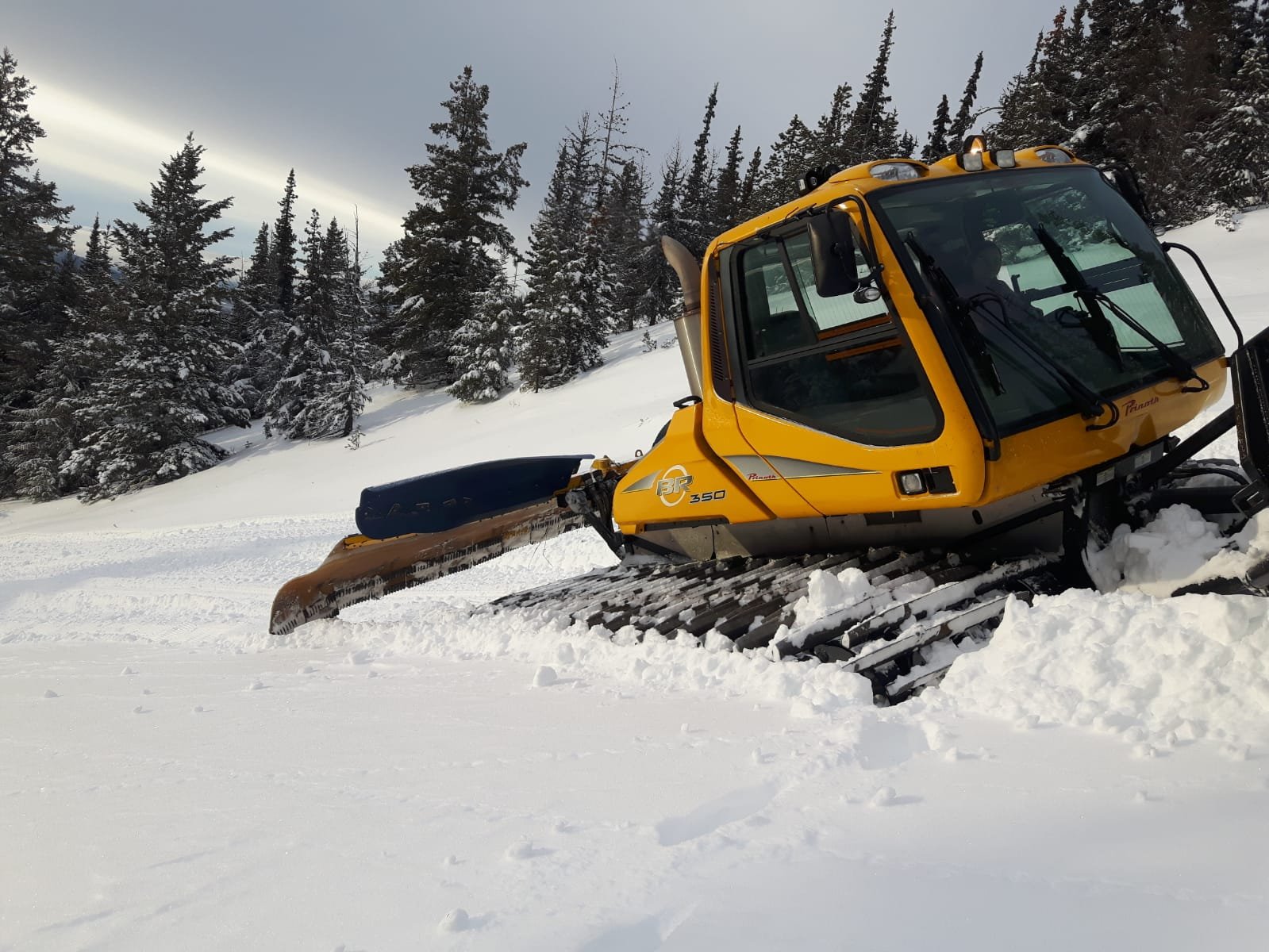 A snowmobile is prominently featured on Murray Ridge in British Columbia Canada with hints of winter sports activities in the background.