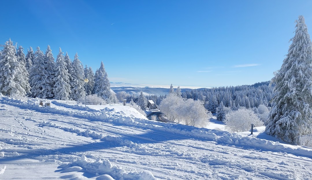 Winter sports enthusiasts enjoying the stunning winter scenery of Lac Blanc in France's Grand-Est region, complete with snow-capped mountains and a thriving ski resort.