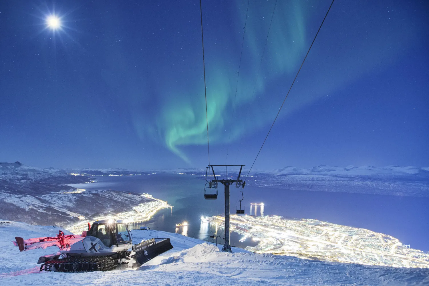 Narvikfjellet – Narvik in Norway - a ski lift going up the mountain with the northern lights in the background.