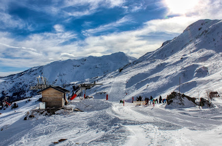 A winter sports scene at the Les Monts d'Olmes ski resort in Occitanie, France featuring a charming chalet amidst a picturesque winter scenery.