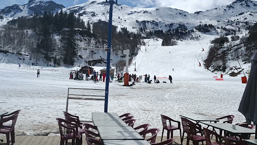 A scenic view of Les Monts d'Olmes ski resort in France featuring a charming challet busy winter sports scene and a ski lift coursing the white