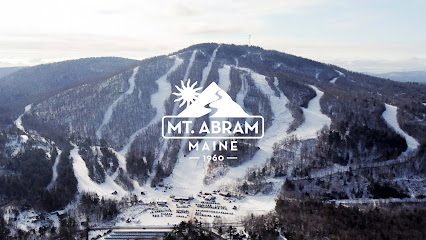A ski resort at Mt Abram in Greenwood Maine featuring snowy slopes and scenic mountain views with visitors engaging in various winter sports.