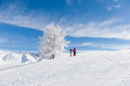 A winter sports scene at a ski resort in Vichères Switzerland featuring a skier gliding down the snow-covered slope with a charming chalet in the background.