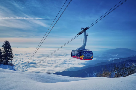 A ski lift cuts through a winter landscape at Biwako Valley ski resort in Kansai, Japan. Skiers navigate the snowy terrain, contributing to the active winter sports scene.