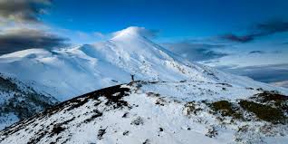 View of the stunning Osorno volcano in Puerto Varas, Chile, covered in thick layers of snow, offering a quintessential winter scenery, ideal for winter sports activities.