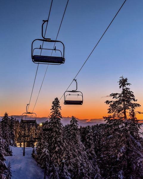 A picturesque winter scene at Kelly Canyon in Ririe Idaho featuring a ski lift ascending a snowy slope. The quaint ski resort and lively winter sports scene exude a fun and festive vibe.