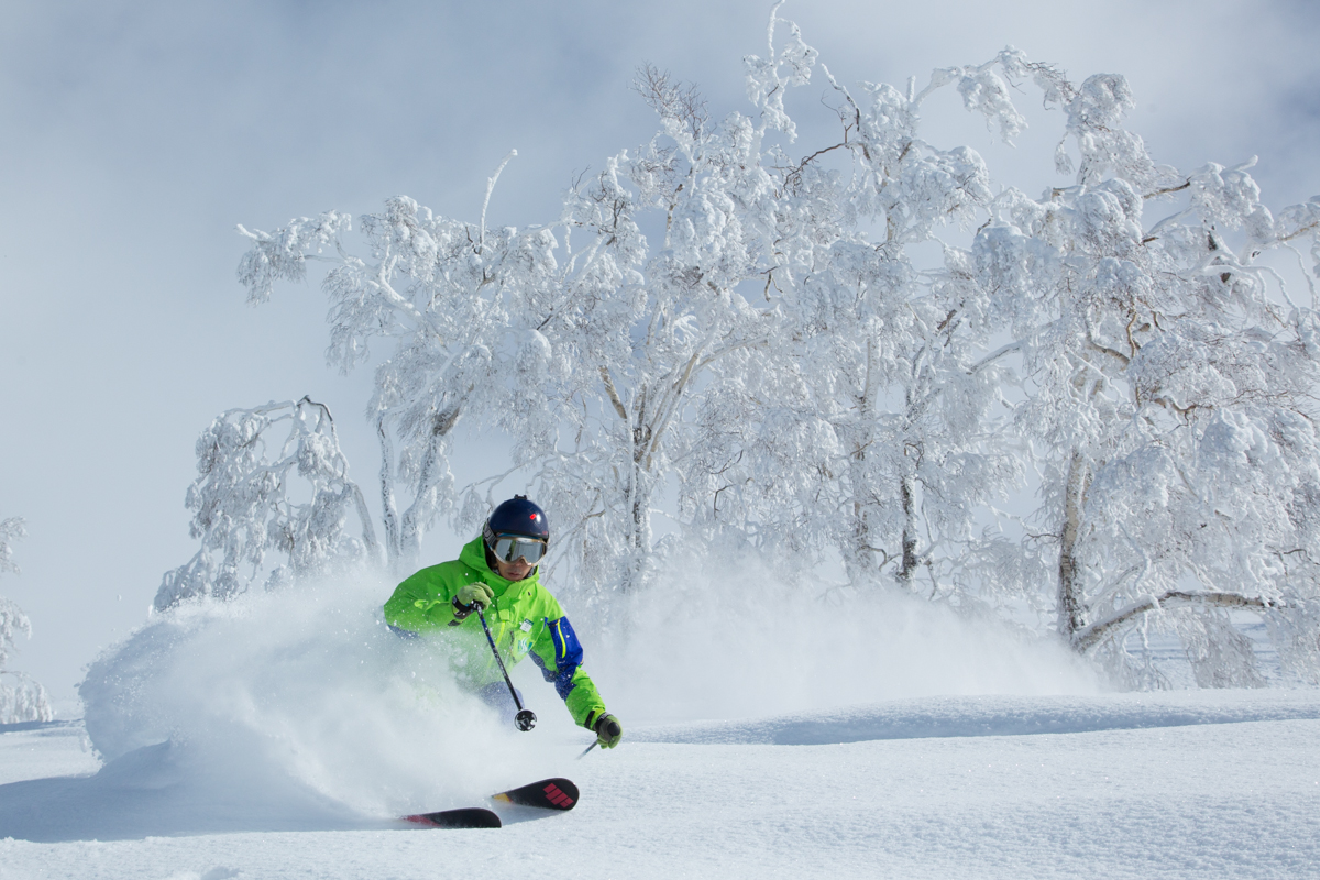 Ojiro in Japan - a person in a green jacket skiing down a hill.