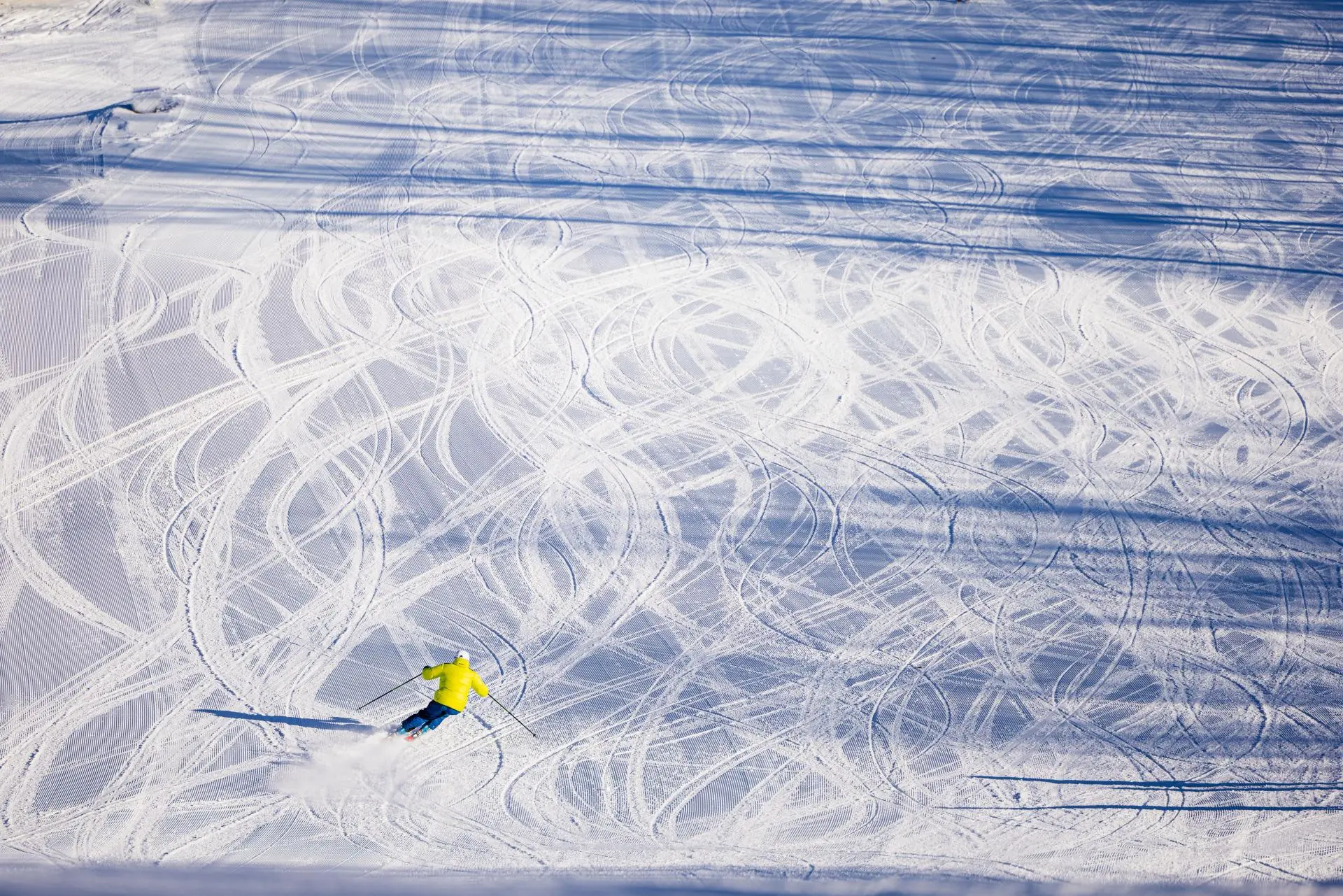 A skier gliding down a snowy slope at Jackson Creek Summit in Wakefield, Michigan, forming a serene winter sports scene, a chalet visible in the distance.