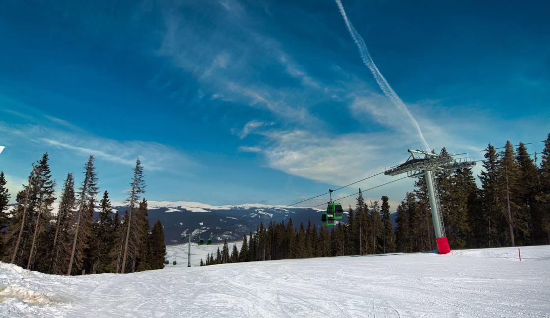 Stunning scene of Transalpina’s ski resort in Romania with visible ski lift and winter sports enthusiasts dotting the snowy landscape enjoying skiing and snowboarding.