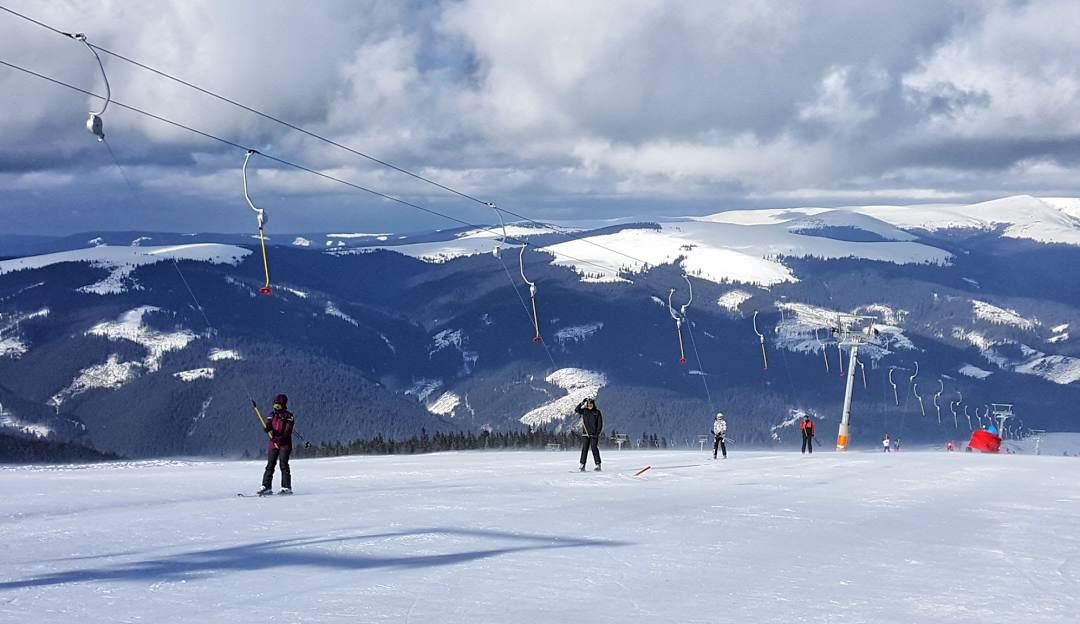 Winter sports scene at the Transalpina Ski Resort in Vidra- Voineasa, Romania, featuring a skier on the slope and a ski lift in operation.