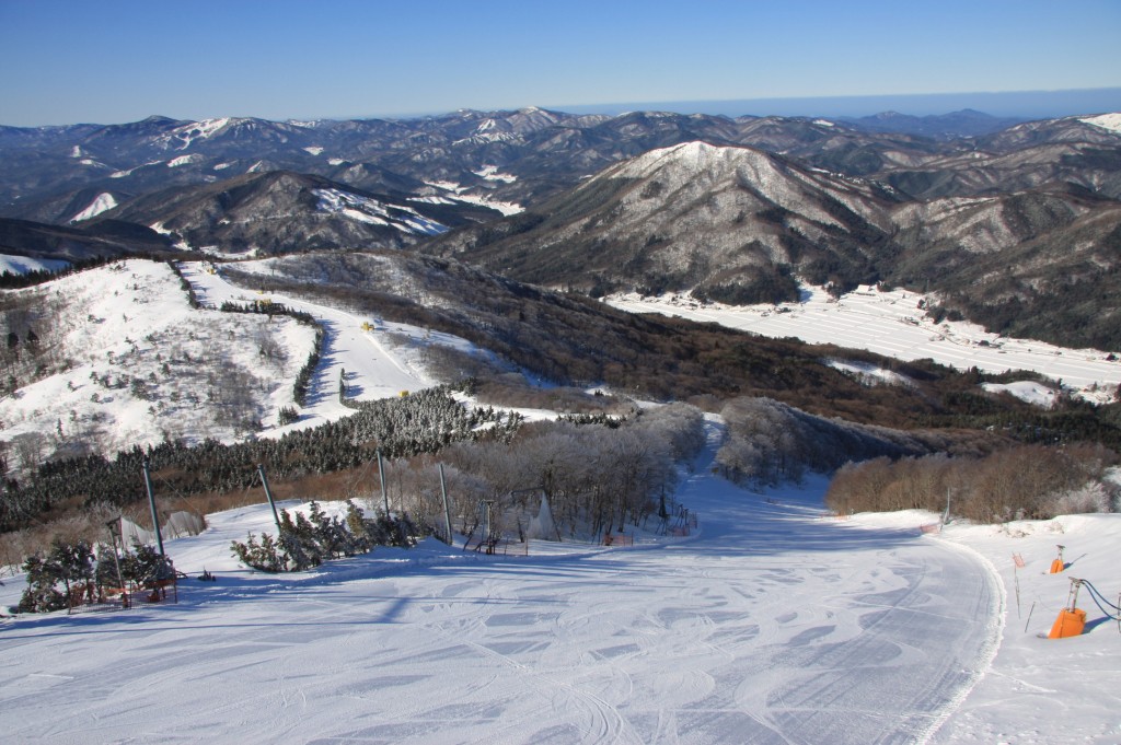 A ski resort in Utopia Saioto, Japan, showcasing snow-covered slopes and activities of winter sports, with a skier descending and a chalet in view.