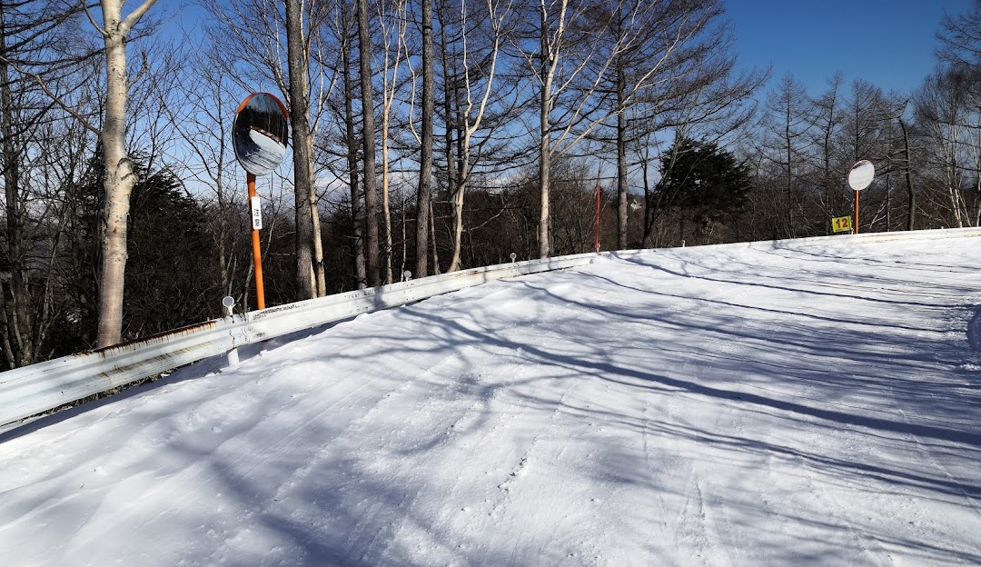 A lively scene from Kusatsu Onsen in Japan featuring a bustling winter sports center. Numerous skiers take to the slopes with the ski lift operating in the background all surrounded by the charm of a ski resort.
