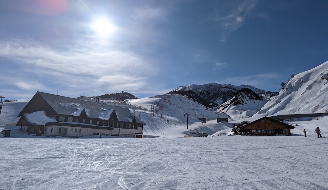 Winter view of Kusatsu Onsen with a ski resort, including a chalet and a winter sports centre visible amidst the snow-covered scenery in Gunma, Japan.