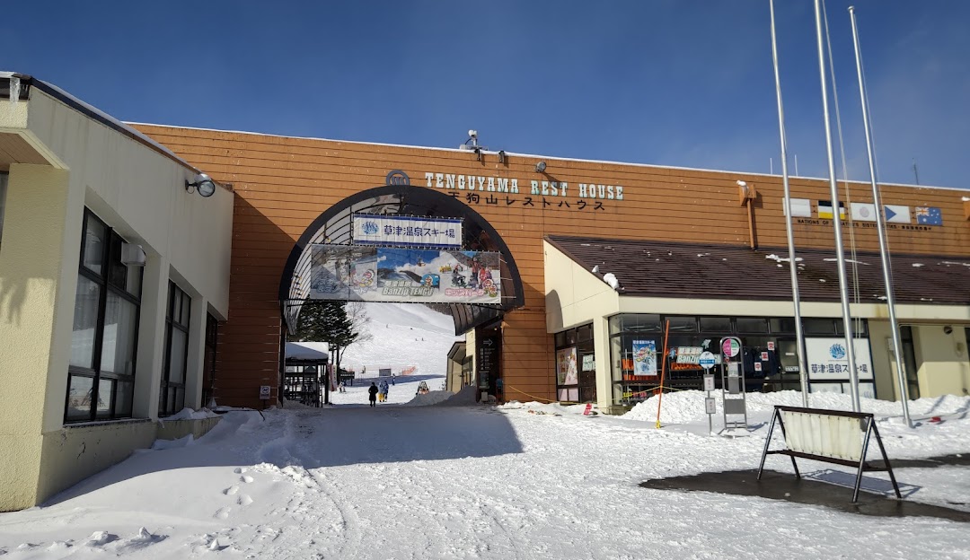 Image showcasing the snowy landscape of Kusatsu Onsen, Kantō, Japan, with a ski resort, winter sports centre, and a ski lift in view amidst the serene winter setting.