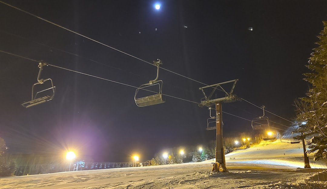 A ski lift operating amidst a winter sports scene at the ski resort of Ichinose Family in Nagano, Japan. Skiers can be seen enjoying the slopes at this popular winter sports centre.