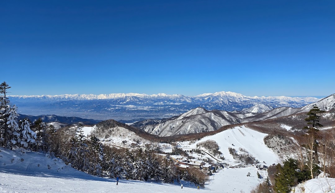 A breathtaking winter scene at Ichinose Family Ski Resort in Nagano Japan. Snow-topped mountains serve as a stunning backdrop for skiers enjoying their winter sports amid the pristine snow-covered scenery.