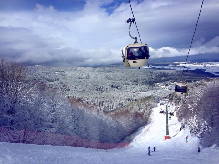 Scenic winter view of Camigliatello Silano in Italy, featuring a ski lift at a ski resort. Skiers enjoy winter sports in this stunning snowy landscape.
