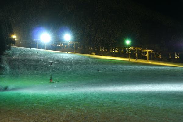 Winter sports activity in full swing at Tateyama Sanroku Raicho Valley, Japan, with a challet and winter sports centre visible amidst the snow-clad slopes as skiers enjoy the terrain.