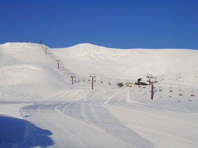 Winter scene at Hyper Bowl Tohachi, a ski resort in Honshu, Japan. The setting includes a sports centre, a charming chalet, and engaging winter sports activity amid a scenic backdrop.