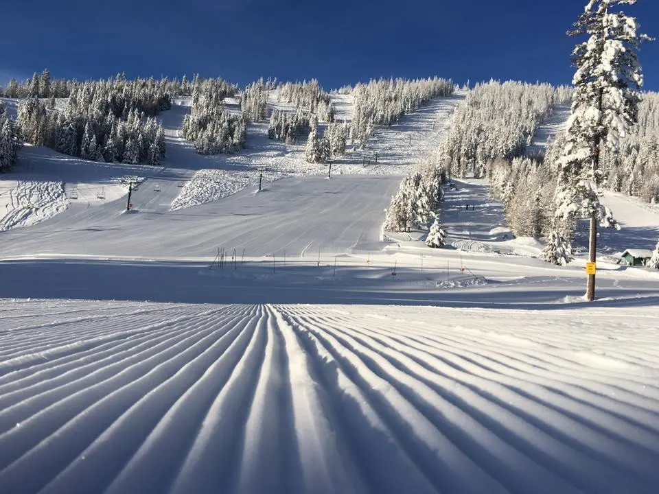 A skier marvels the wintertime beauty of Loup Loup Ski Bowl in Okanogan Washington immersed in thrilling winter sports amid snow-covered slopes. Nearby a snowmobile rests