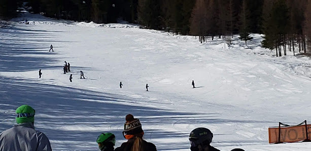 A skier glides down a snowy slope at Loup Loup Ski Bowl in Okanogan Washington with other skiers scattered nearby. A chalet can be seen in the distance at this picturesque winter sports resort.