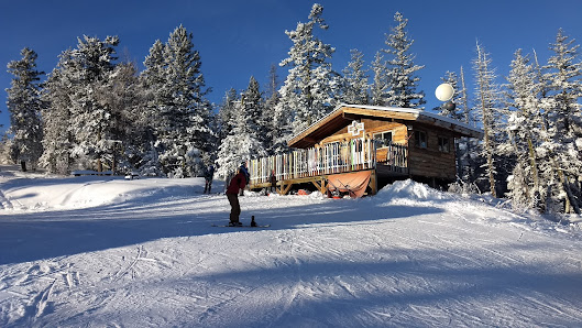 Winter scene at Loup Loup Ski Bowl in Okanogan, Washington, showcasing stunning snowy mountains, a lodge, and a snowmobile, indicating a fun-filled ski resort.