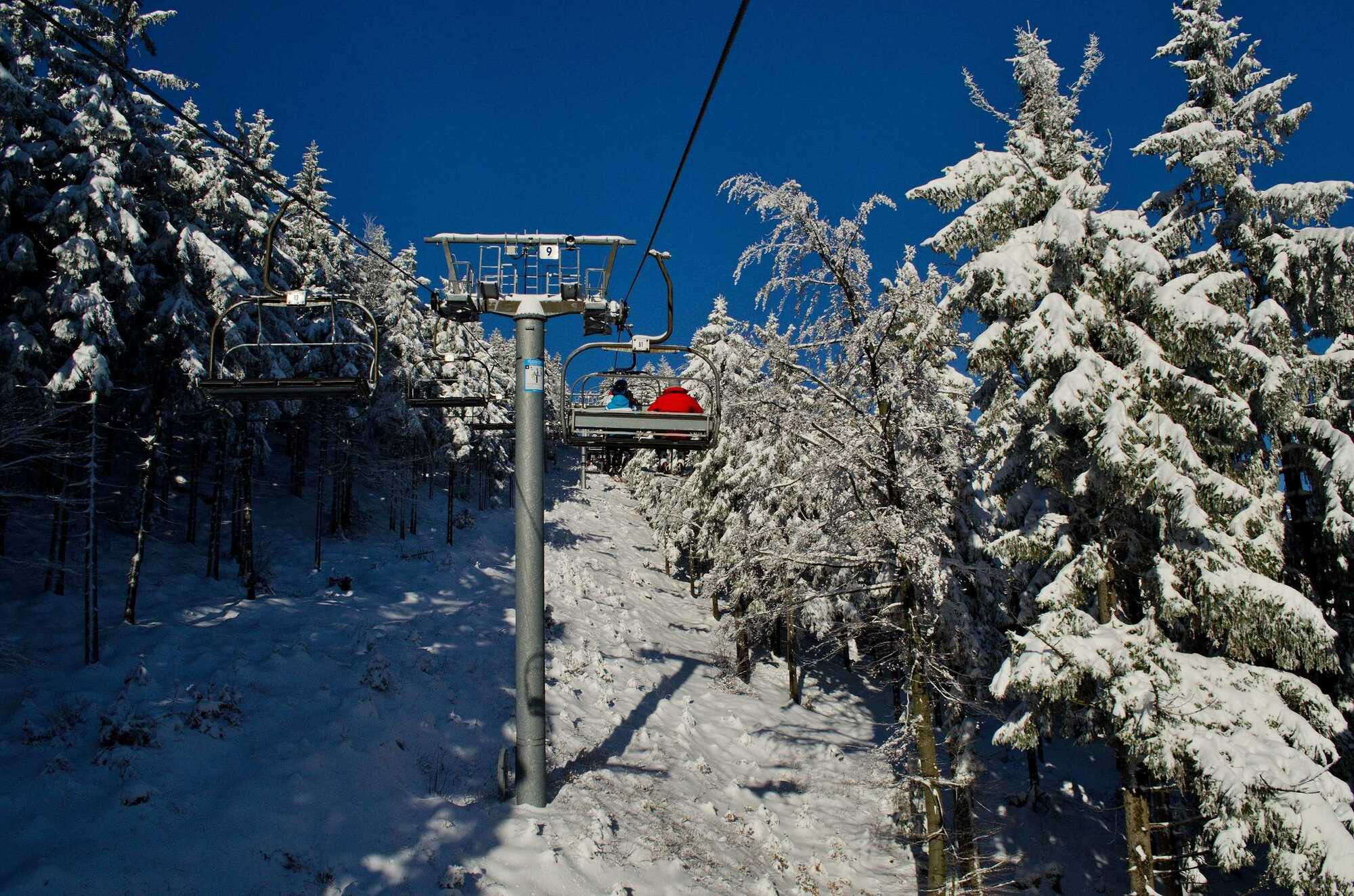 Ski lift rising above a stunning winter panorama at Říčky Ski Center, complete with a charming chalet amidst the snow-covered landscape in the Hradec Králové Region of Czech Republic.