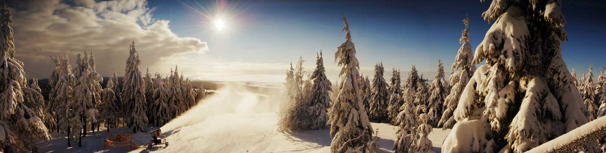 Winter view of Ski center Říčky in the Czech Republic, showing a bustling winter sports scene amidst a breathtaking snowy landscape, parts of a ski resort, and a cozy challet.