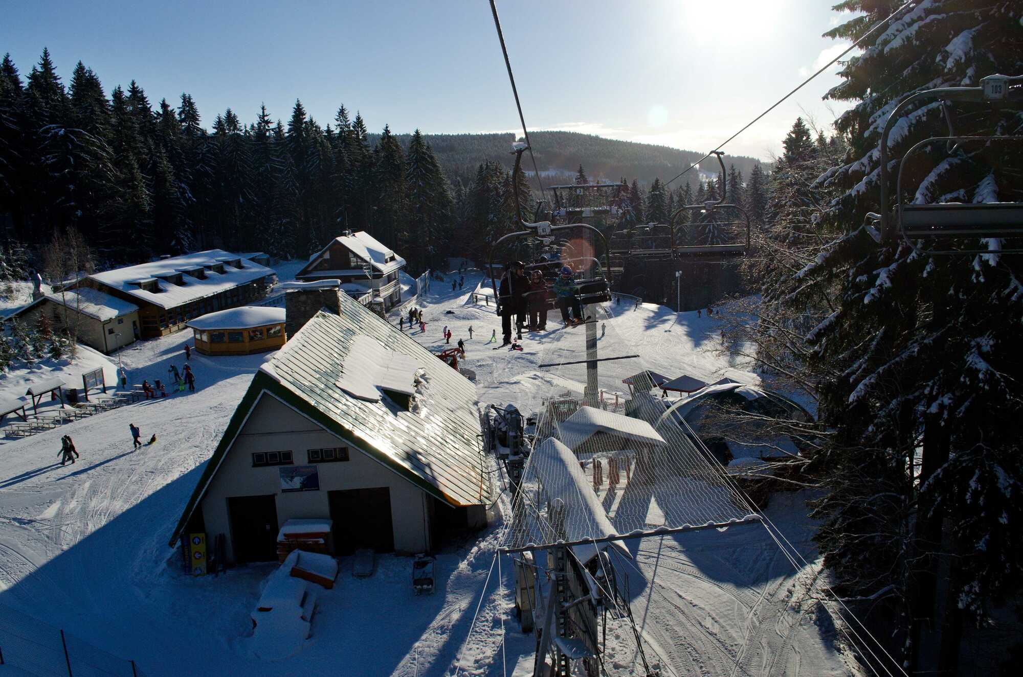A lively winter sports scene at Ski center Říčky in Hradec Králové Region Czech Republic. Skiers are ascending the slope via a ski lift preparing for exhilarating downhill runs. A charming challet is nestled nearby.