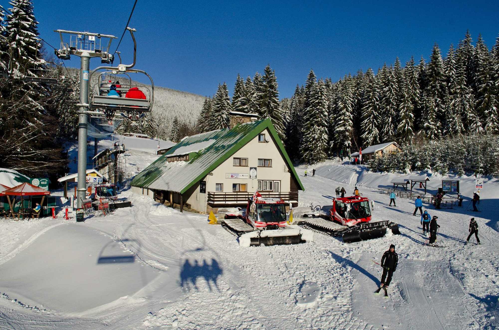 A lively ski resort in Říčky v Orlických horách Czech Republic bustling with winter sports activities. Features include a ski lift and a cozy challet amidst a winter sports scene.