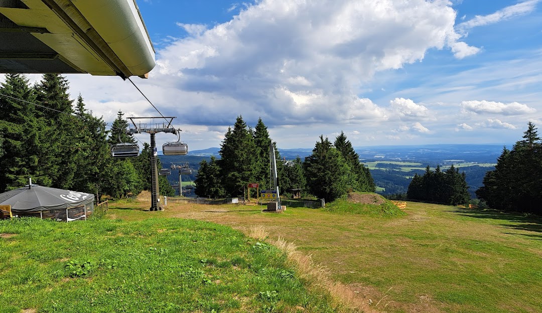 Ski lift ascending a snow-covered slope at the Říčky Ski Center in the Hradec Králové Region, Czech Republic, with a chalet nestled amidst the winter landscape.