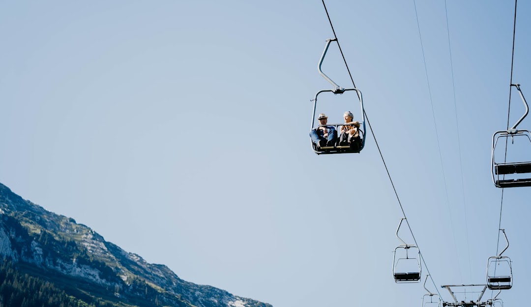 Image of a ski lift at Sesselbahn Mattstock a part of the Skigebiet Mattstock Amden ski resort in Eastern Switzerland. A chalet can be seen in the backdrop of a beautiful mountain.