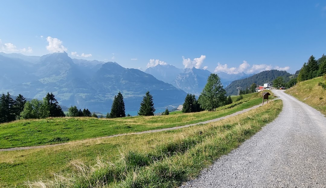 A sunny day at Sesselbahn Mattstock ski resort in Amden, Eastern Switzerland. In focus is a charming chalet nestled against the backdrop of a mountain. A mountain bike rests nearby.