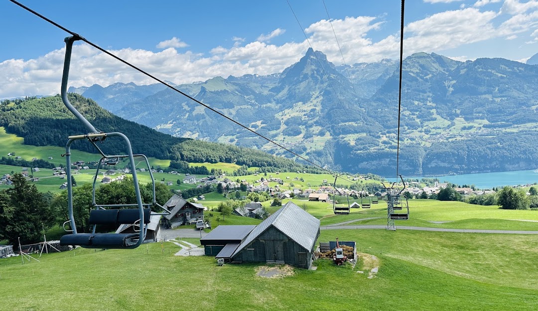View from the Sesselbahn Mattstock ski resort in St. Gallen, Switzerland featuring a ski lift ascending the mountain with distant skier and chalet.