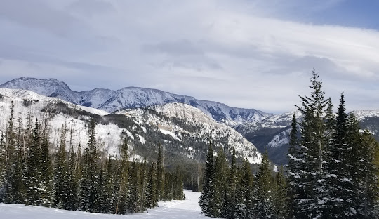 A lively winter sports scene at Teton Pass ski resort in Choteau Montana. Skiers traverse the snowy terrain of the mountain contributing to the beautiful winter scenery.