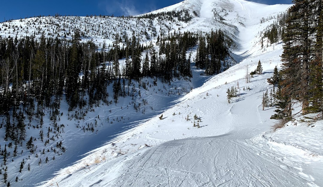 A winter view of the ski resort at Teton Pass in Choteau Montana featuring idyllic snow-covered slopes and a skier elegantly maneuvering. A ski lift adds to the picturesque atmosphere of the winter sports scene.