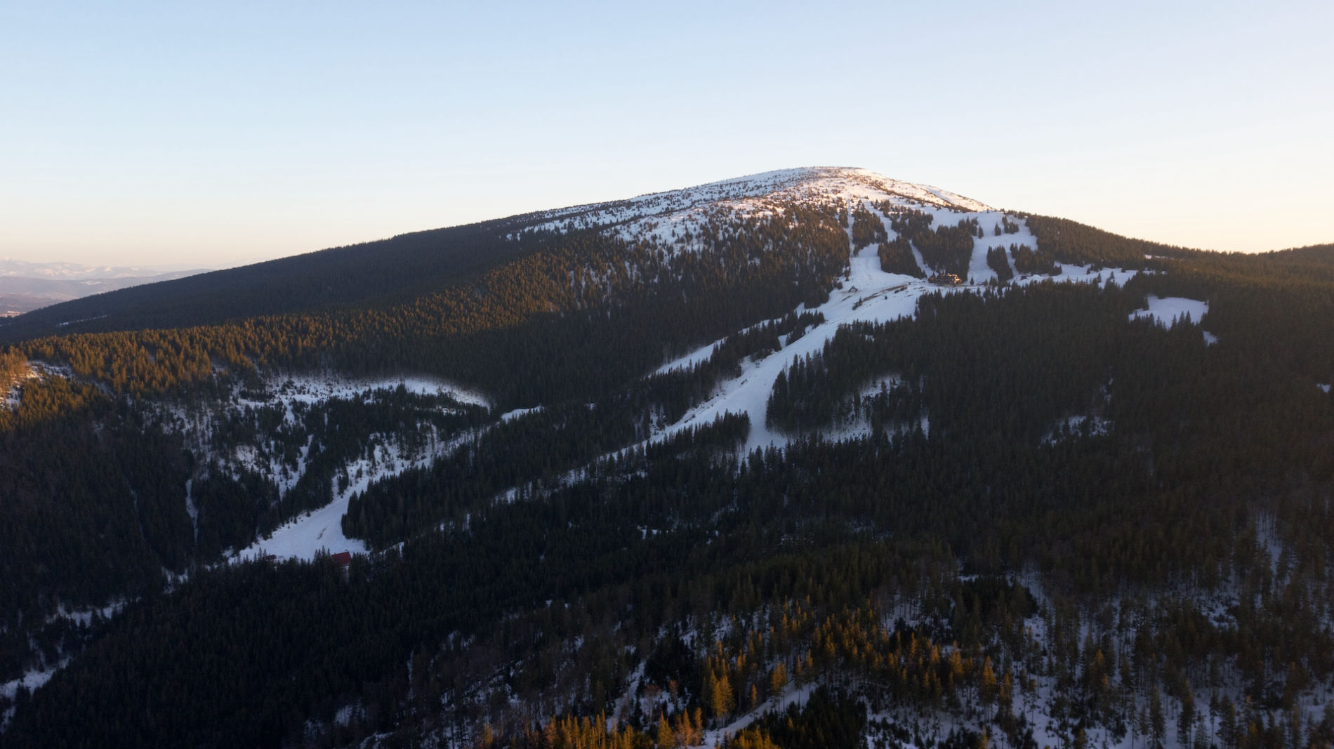 A picturesque view at Pilsko-Korbielów in Poland featuring a mountain covered in snow the busy slopes of a ski resort and a ski lift